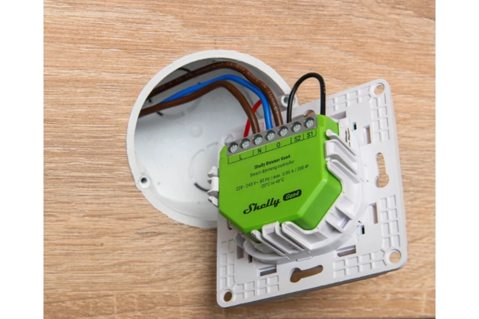 A Shelly Dimmer Gen4 wired into a wall box behind a light switch frame