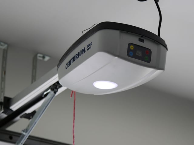 A ceiling-mounted garage door opener with its drive rail running back into the garage