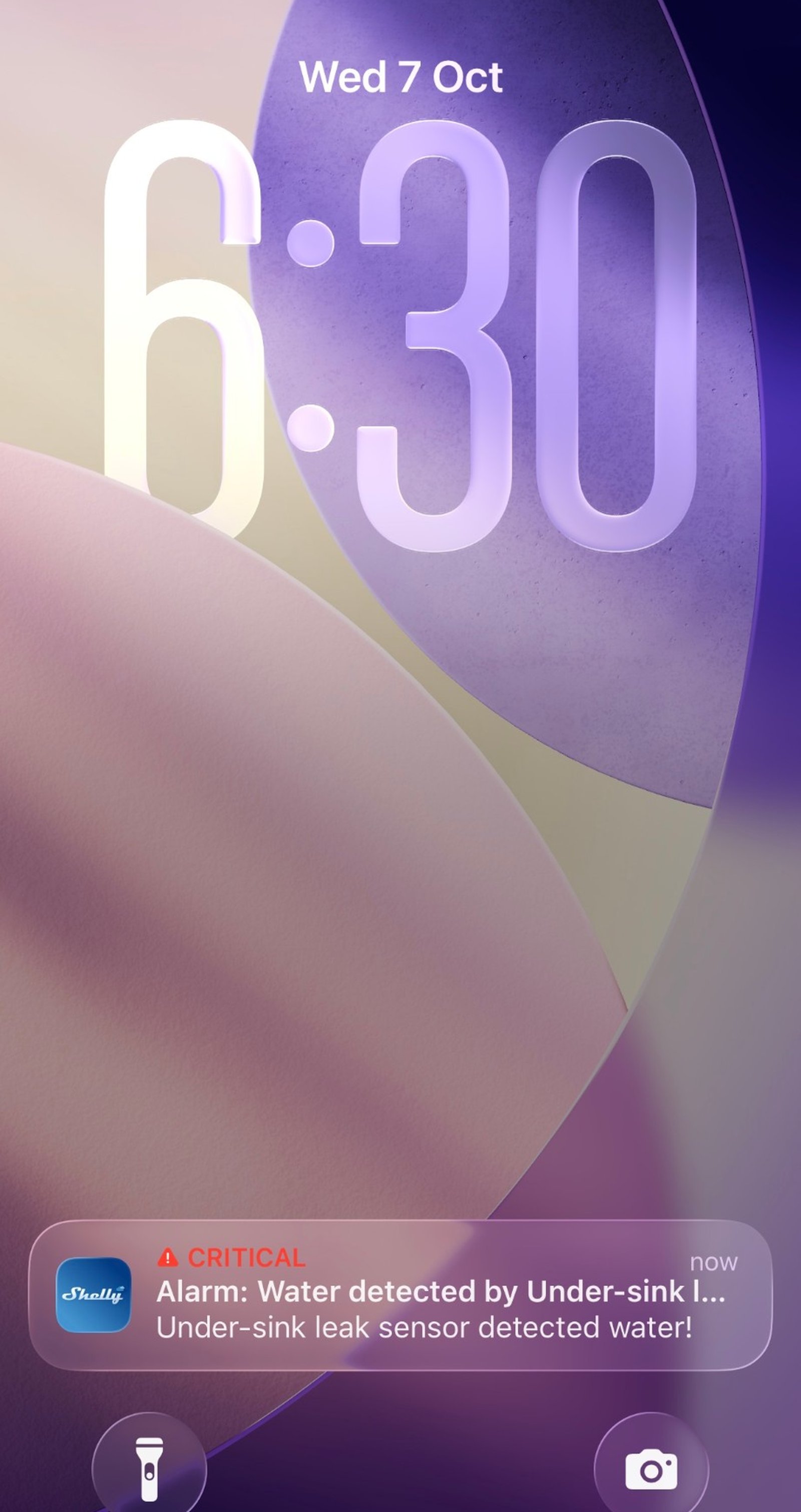 iPhone lock screen showing a critical Shelly alert that water was detected by a sensor named Under-sink leak sensor.