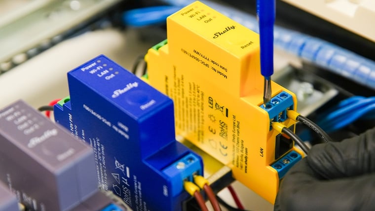 Shelly Pro RGBWW PM being wired into a DIN rail cabinet with a screwdriver