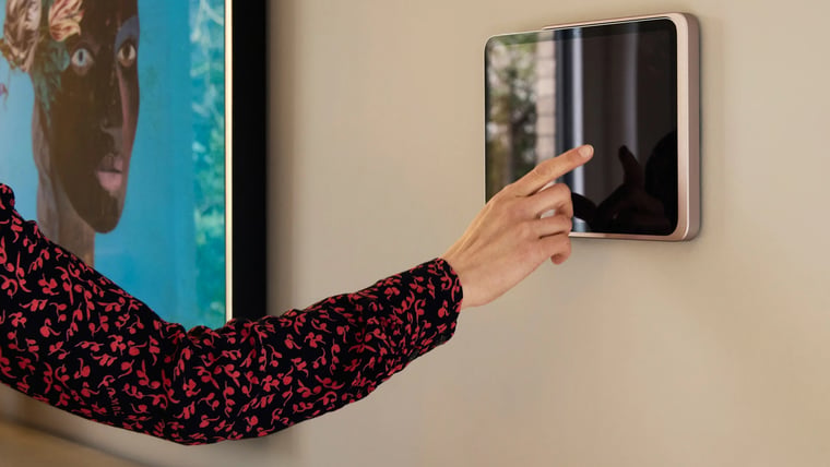A person tapping an iPad held in a rose gold Displine Dame Wall Home 2.0 on a wall