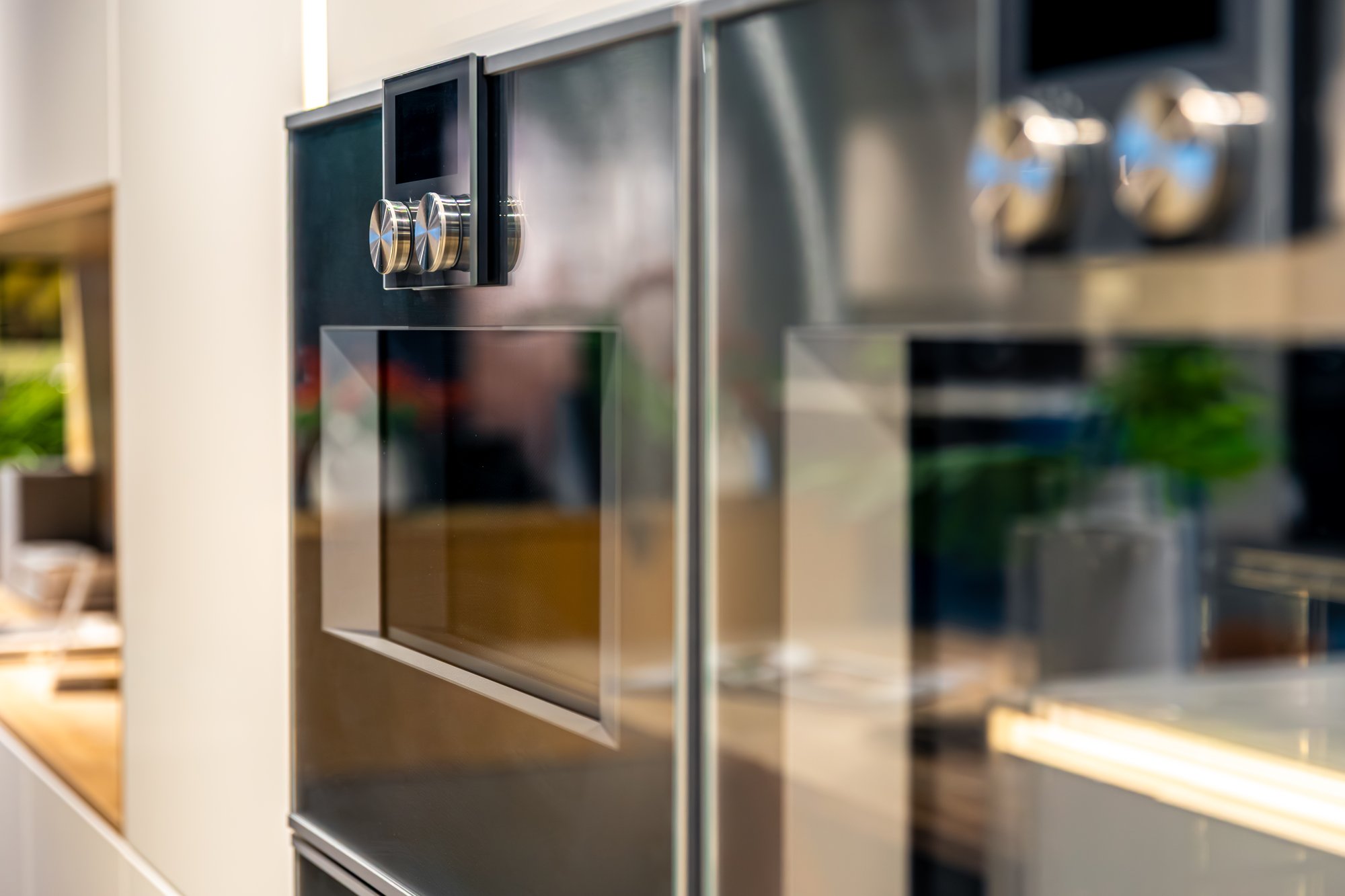 Two built-in stainless steel wall ovens in a kitchen, close up on the control dials