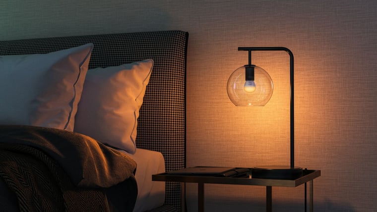 A Hue lamp lit warm on a bedside table
